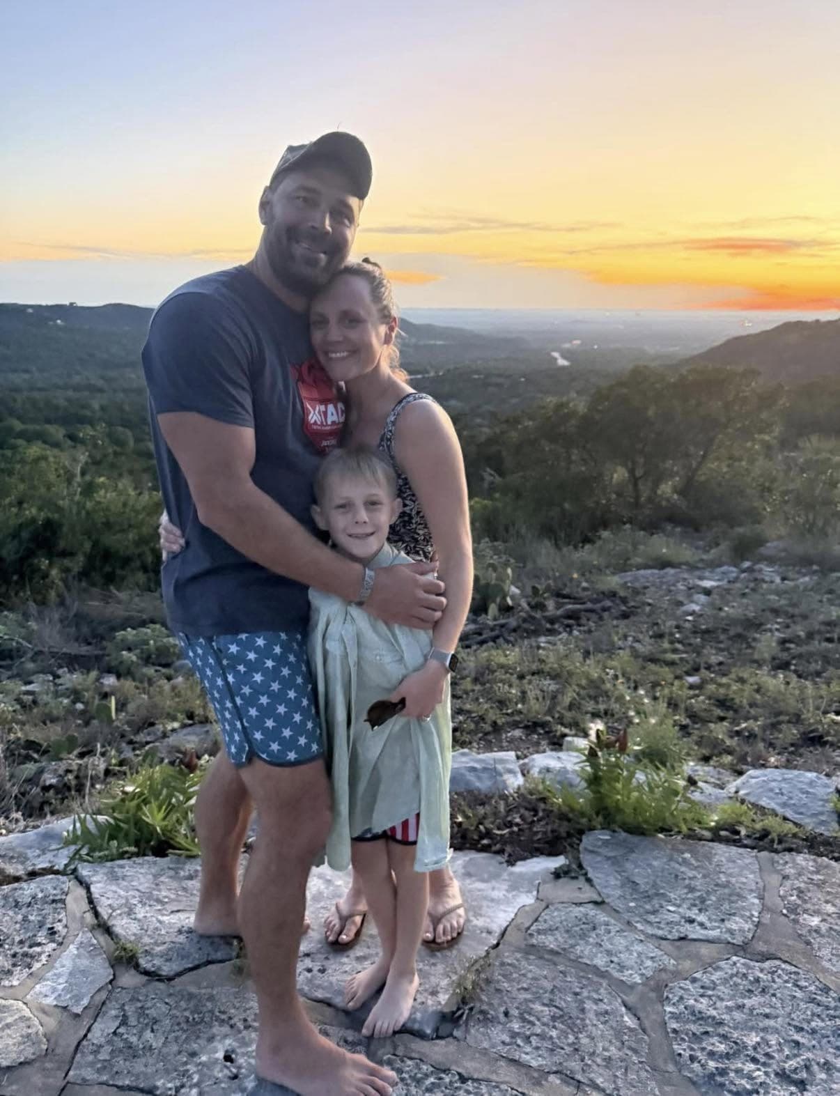 Mike and Natalie Evans with their son on a limestone overlook, the Hill Country behind them at sunset