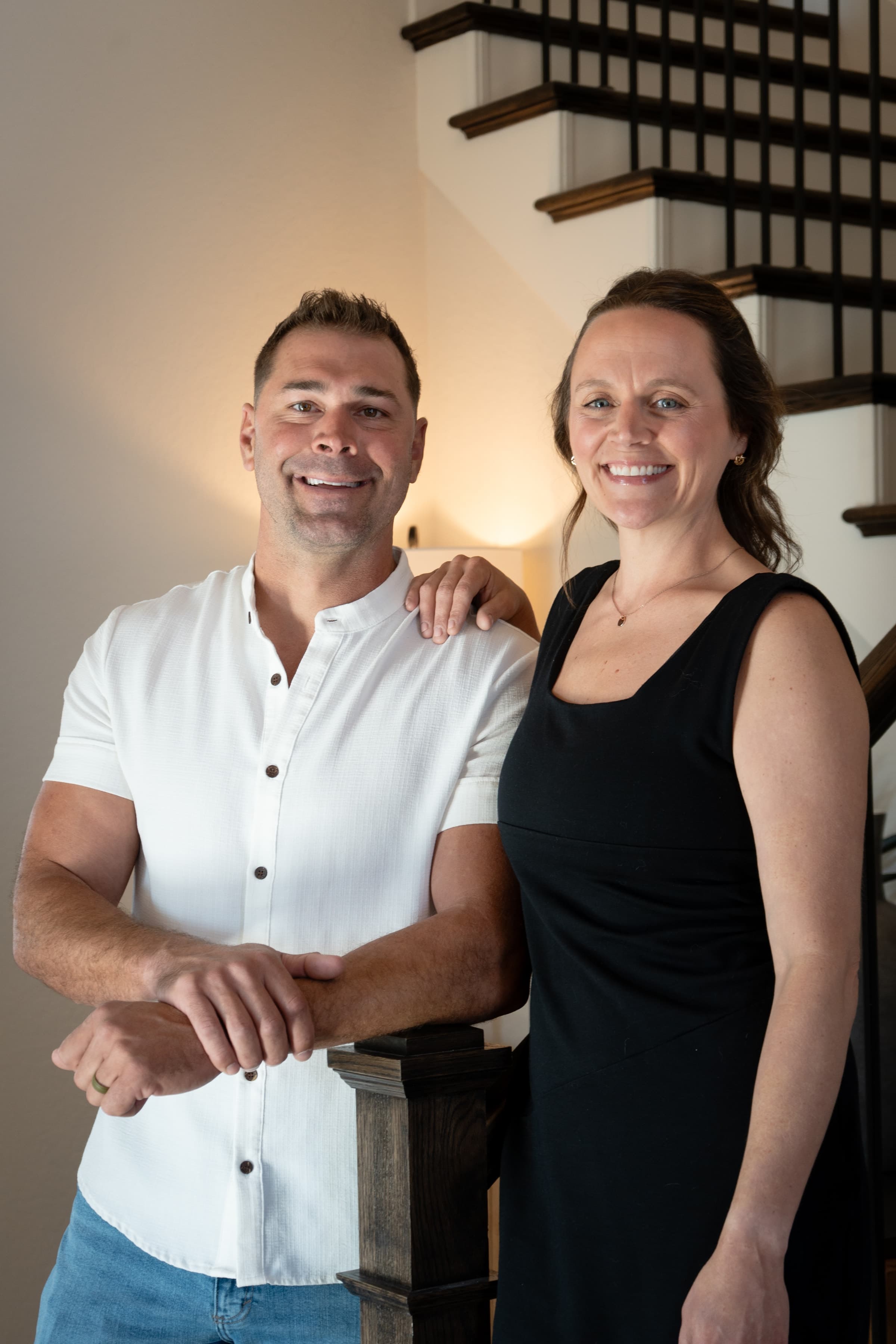 Mike and Natalie Evans of Rucking Realty Group, standing together at the foot of a staircase